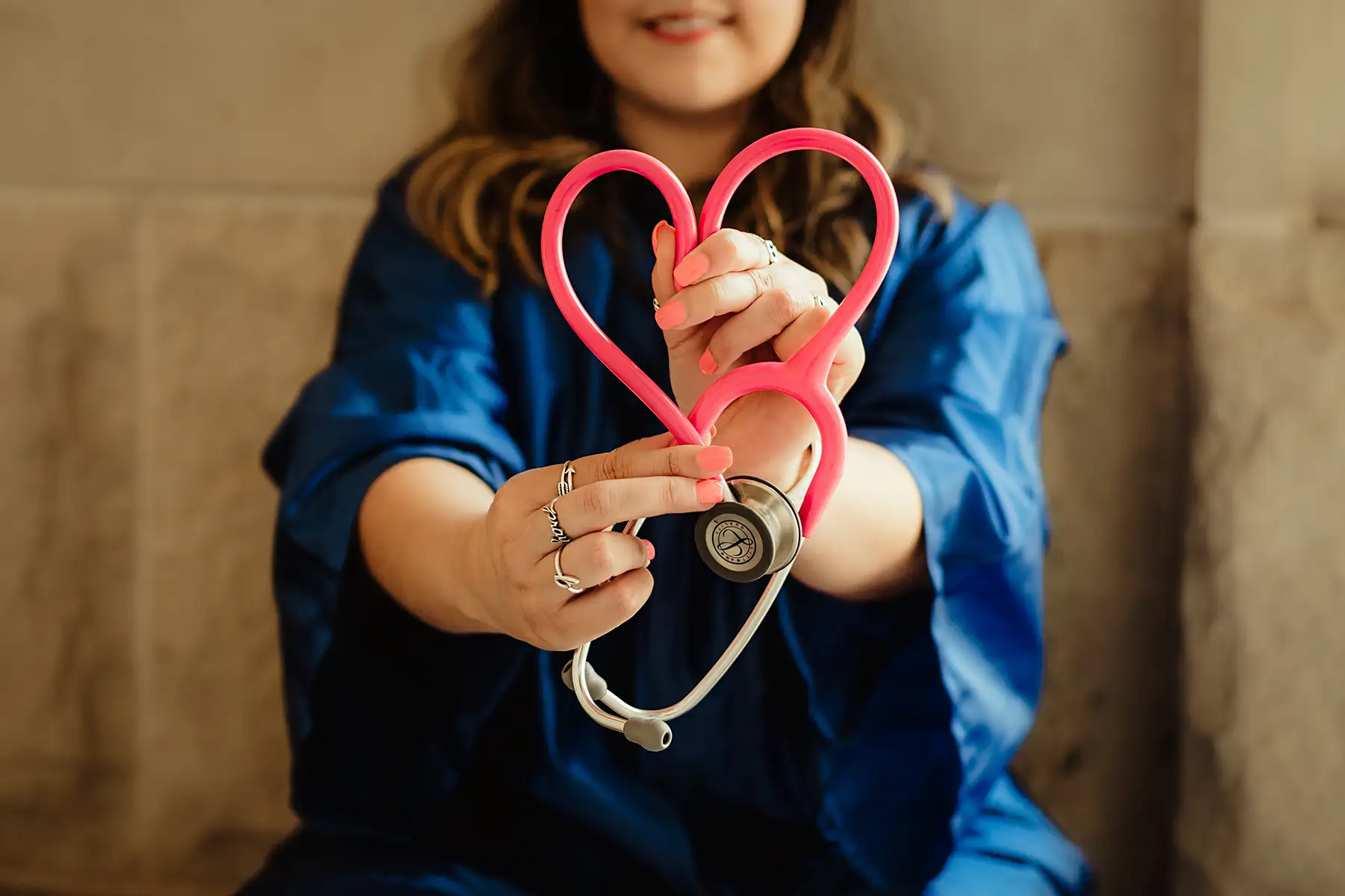 image of woman holding up stethoscope with red tubing in the shape of a heart